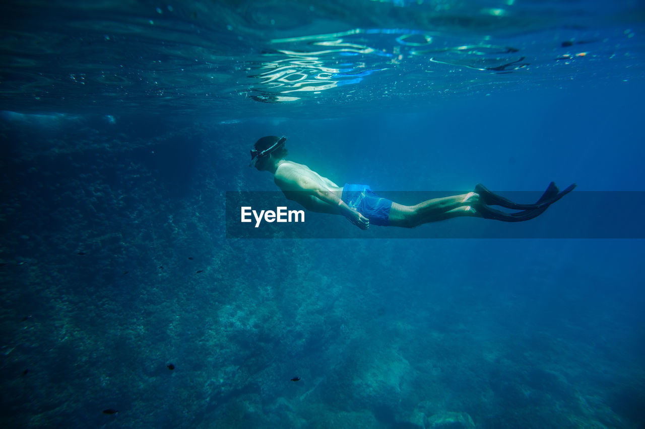 Shirtless young man scuba diving in sea