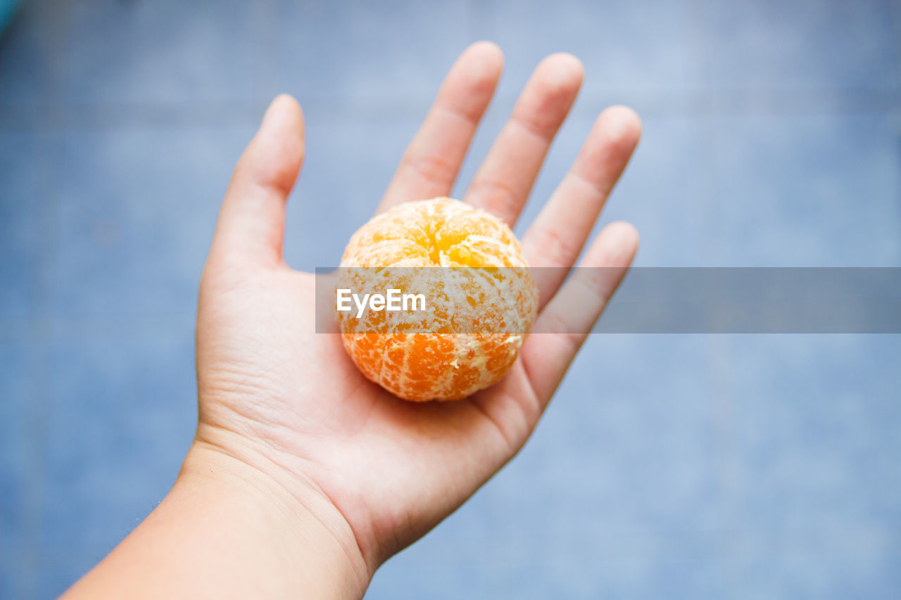 Close-up of hand with peeled orange on palm