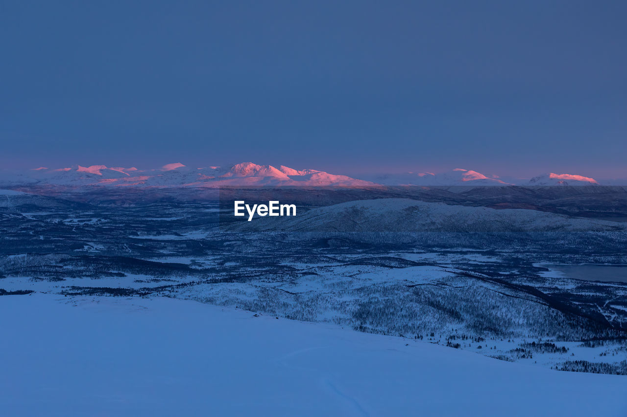 Scenic view of snowcapped mountains against clear sky during sunset