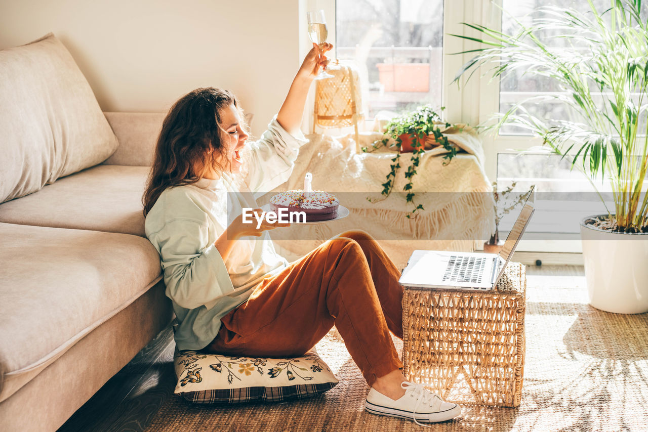 MIDSECTION OF WOMAN SITTING ON SOFA AT HOME