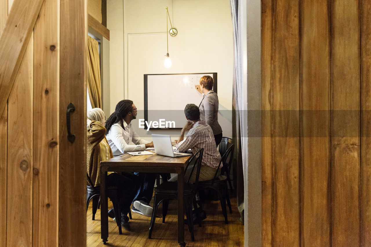 Businesswoman writing on whiteboard in creative office