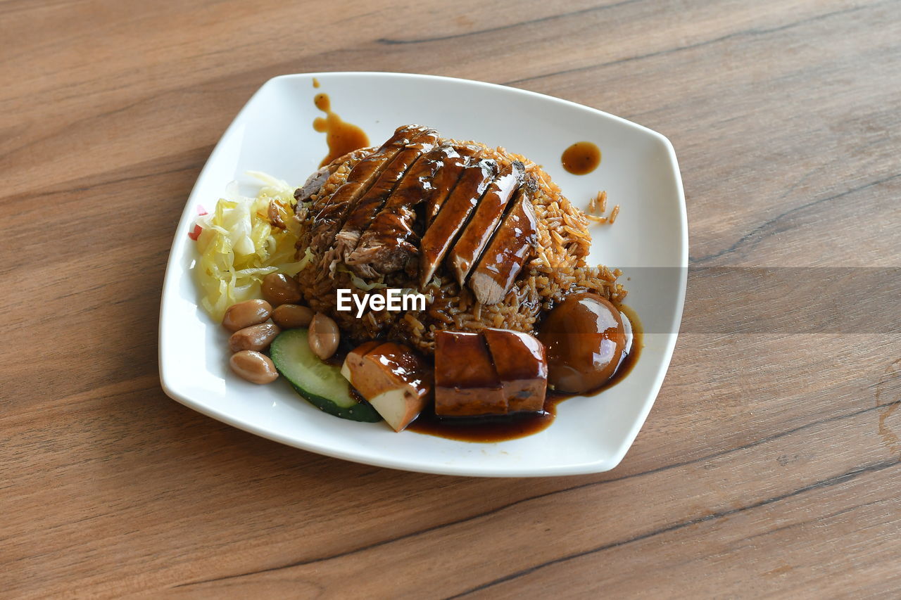 Braised duck rice served in plate on wooden table