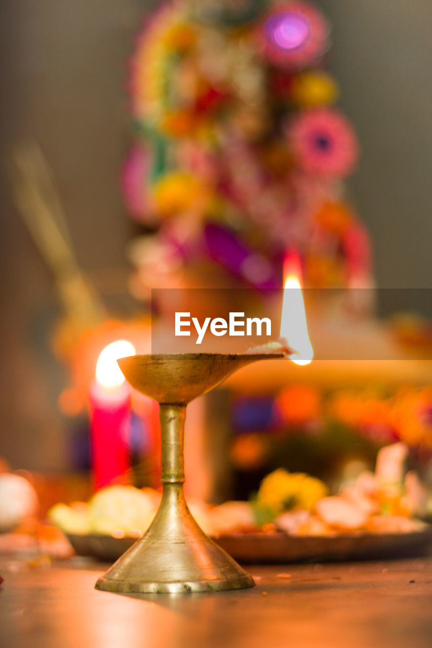 CLOSE-UP OF ILLUMINATED LAMP ON TABLE AGAINST BLURRED BACKGROUND