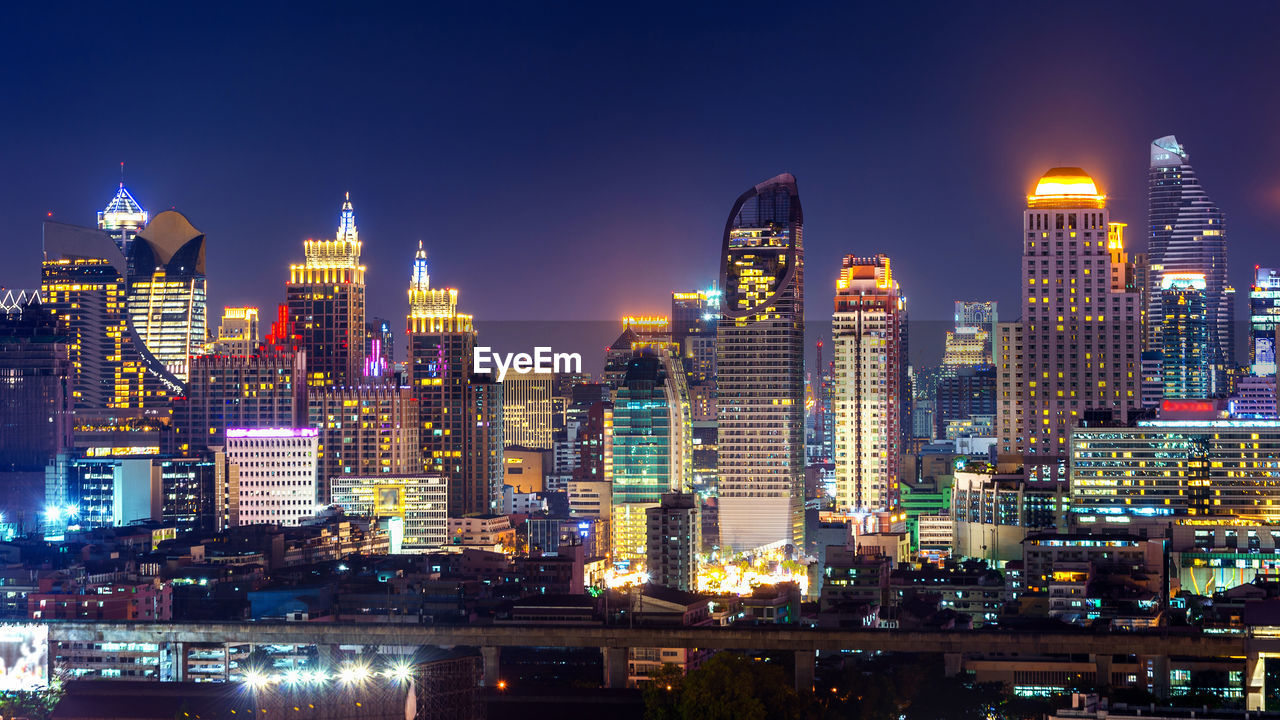 Illuminated buildings in city against sky at night