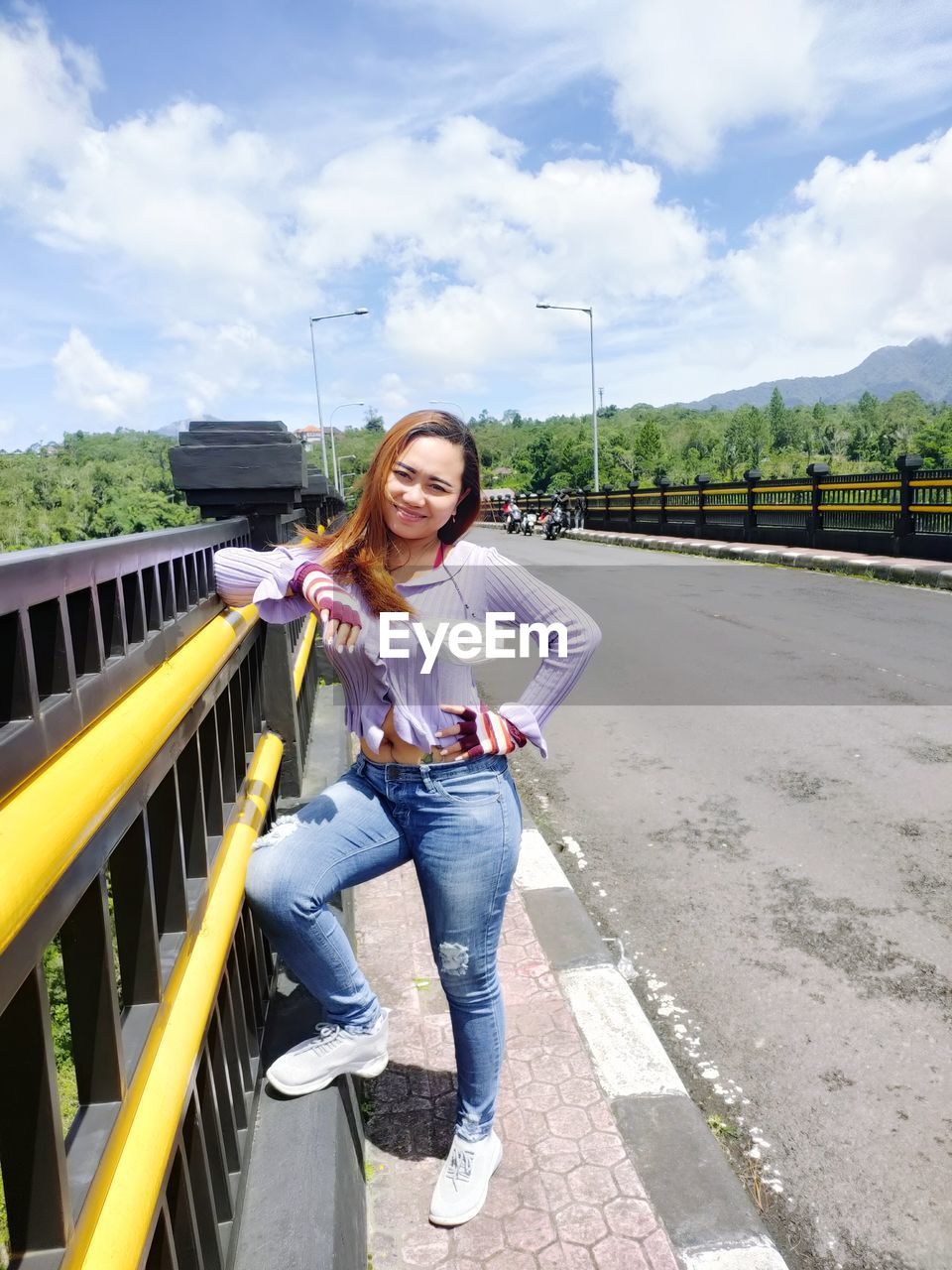 PORTRAIT OF BEAUTIFUL YOUNG WOMAN STANDING AGAINST RAILING