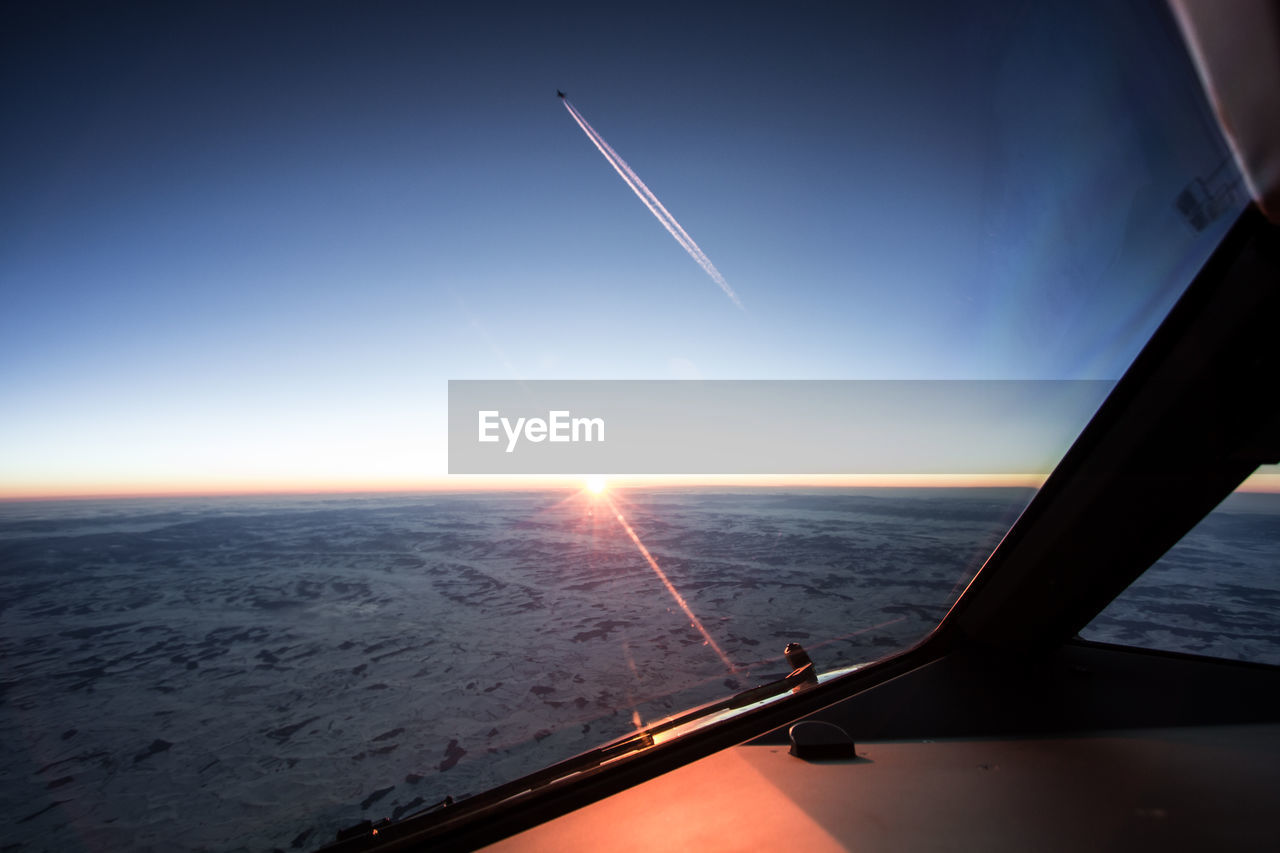 View of landscape seen through airplane window during sunset