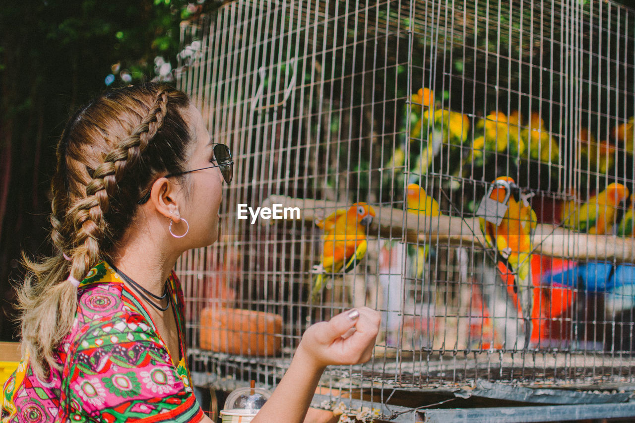 Woman looking at birds in cage