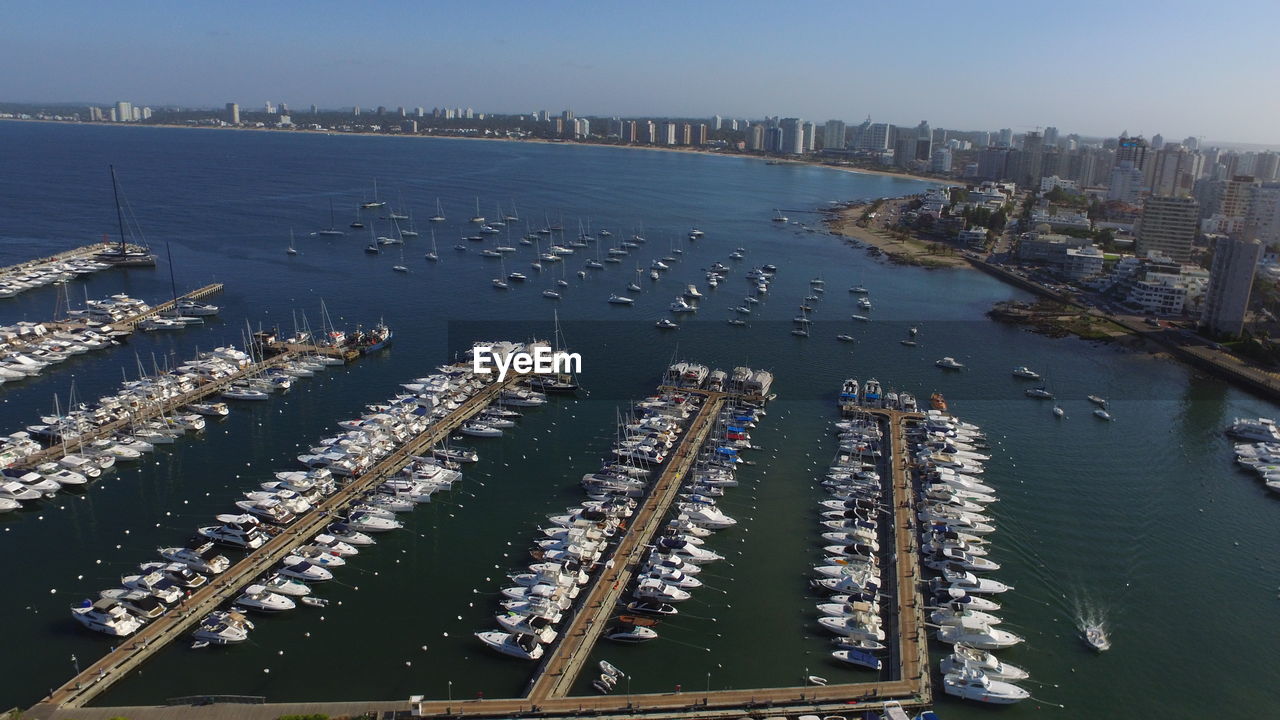 HIGH ANGLE VIEW OF CITY BY SEA AGAINST SKY