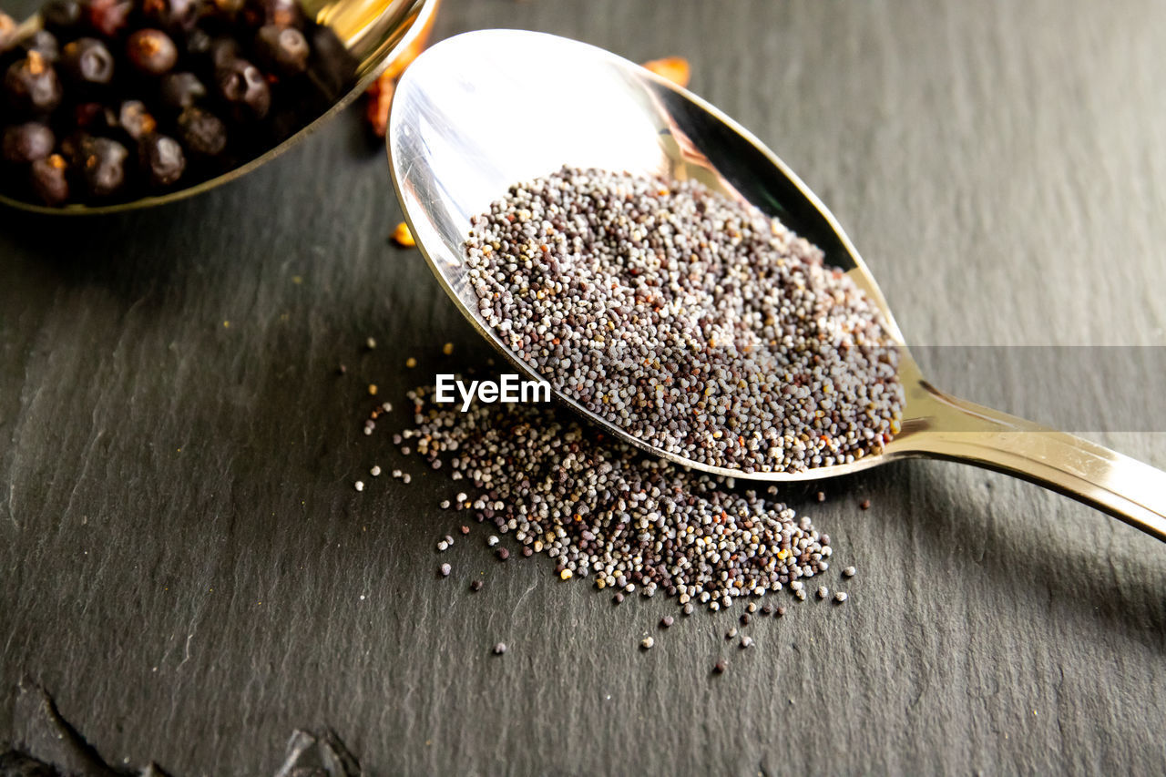 Composition with poppy seeds in spoon on stone background