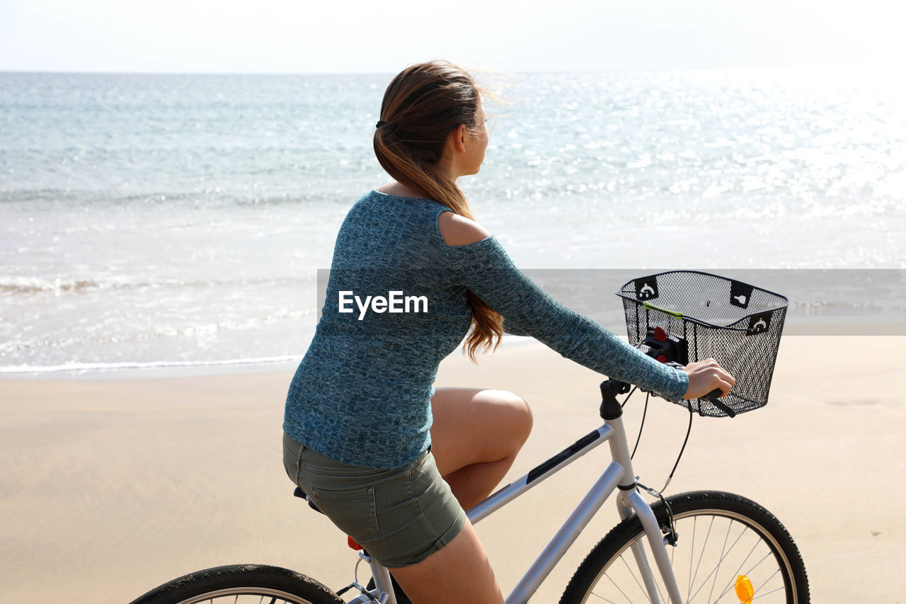 Woman riding bicycle on beach