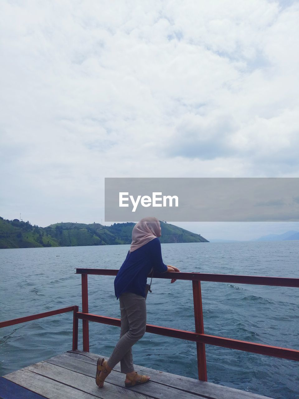 REAR VIEW OF MAN STANDING AGAINST SEA