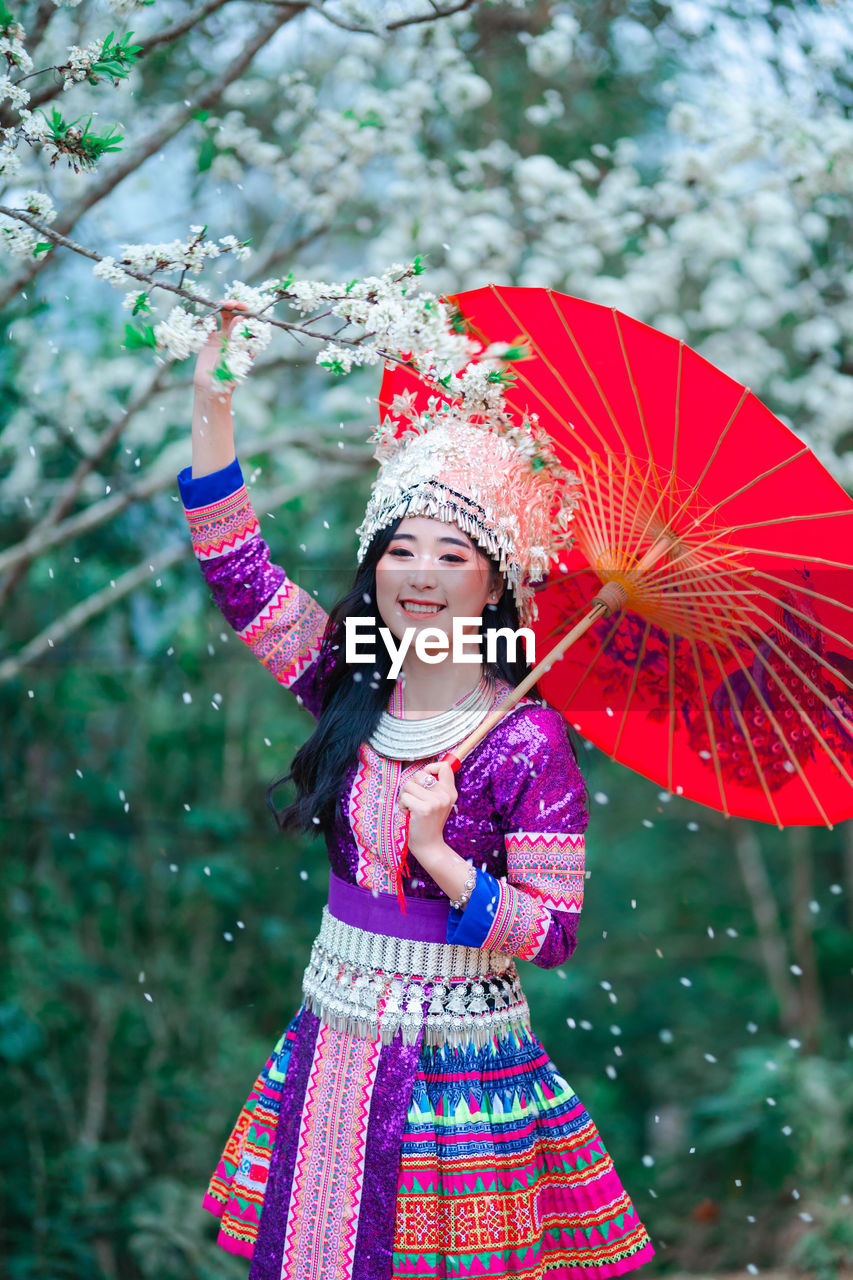 Low angle view of smiling girl standing against tree