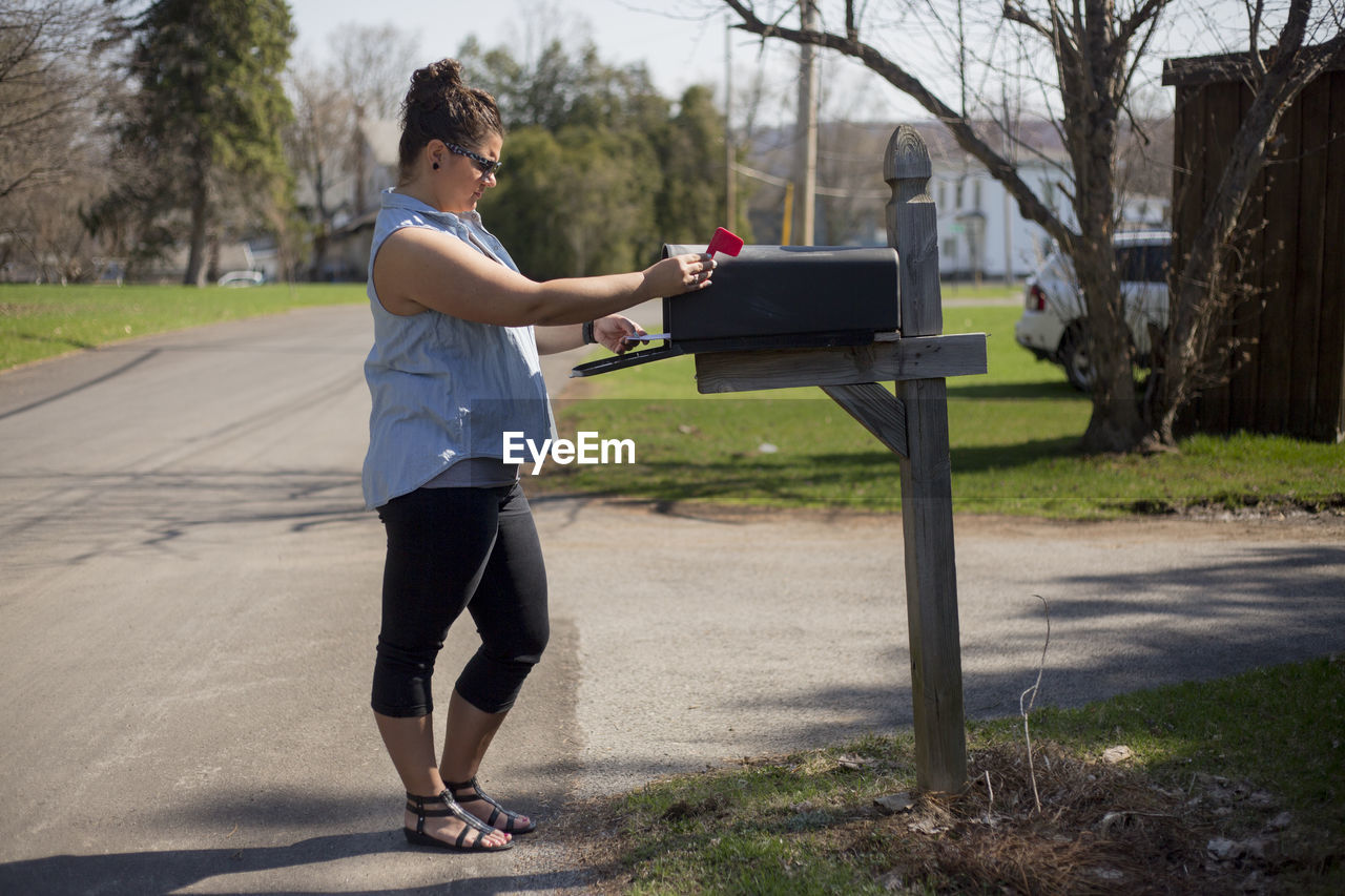 Side view of young woman standing by mailbox on street