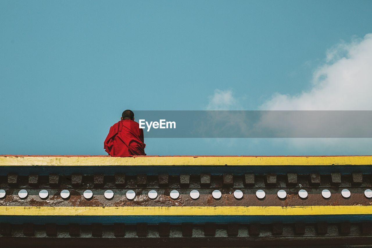 Rear view of a monk against blue sky