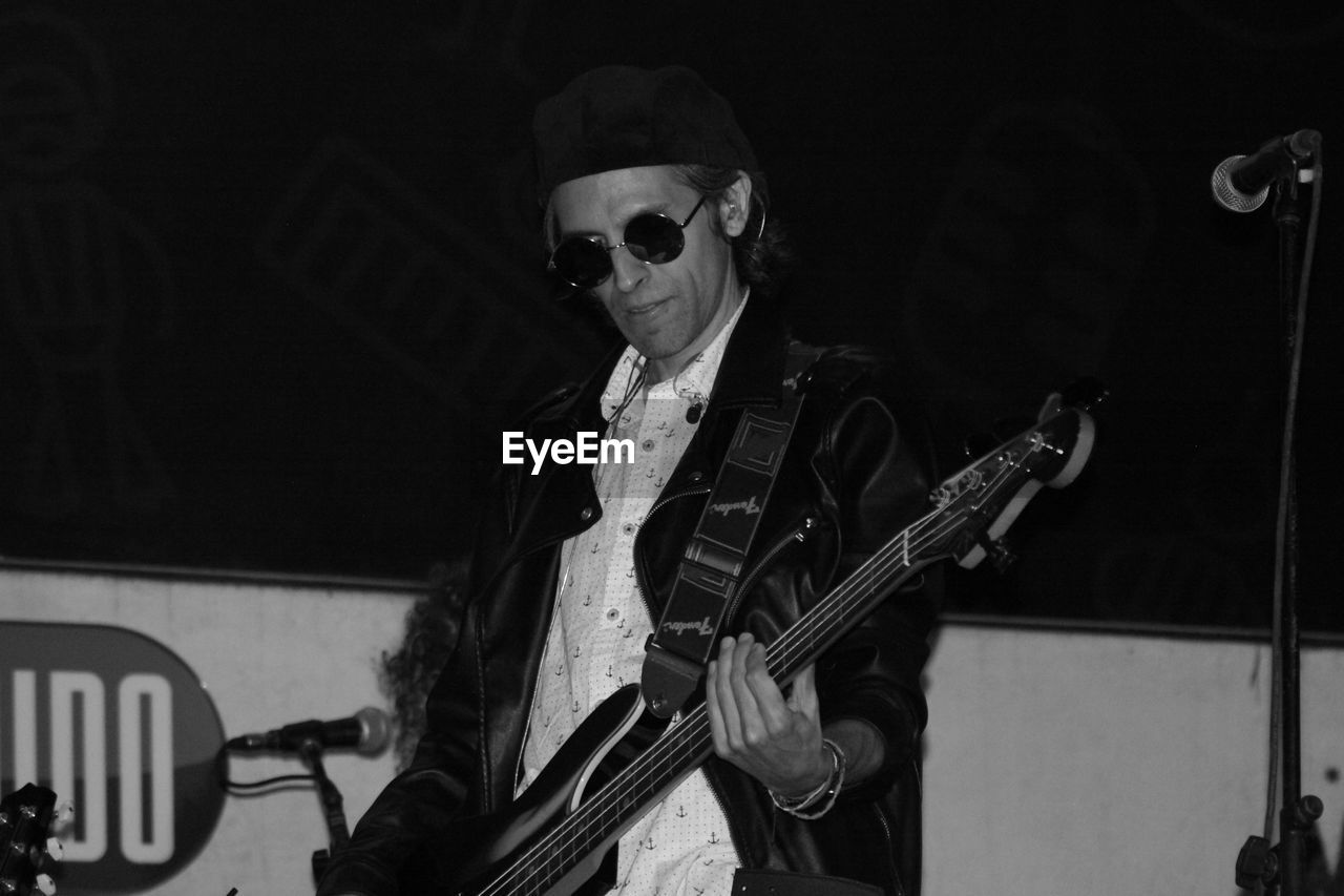 YOUNG MAN PLAYING GUITAR AT MUSIC CONCERT