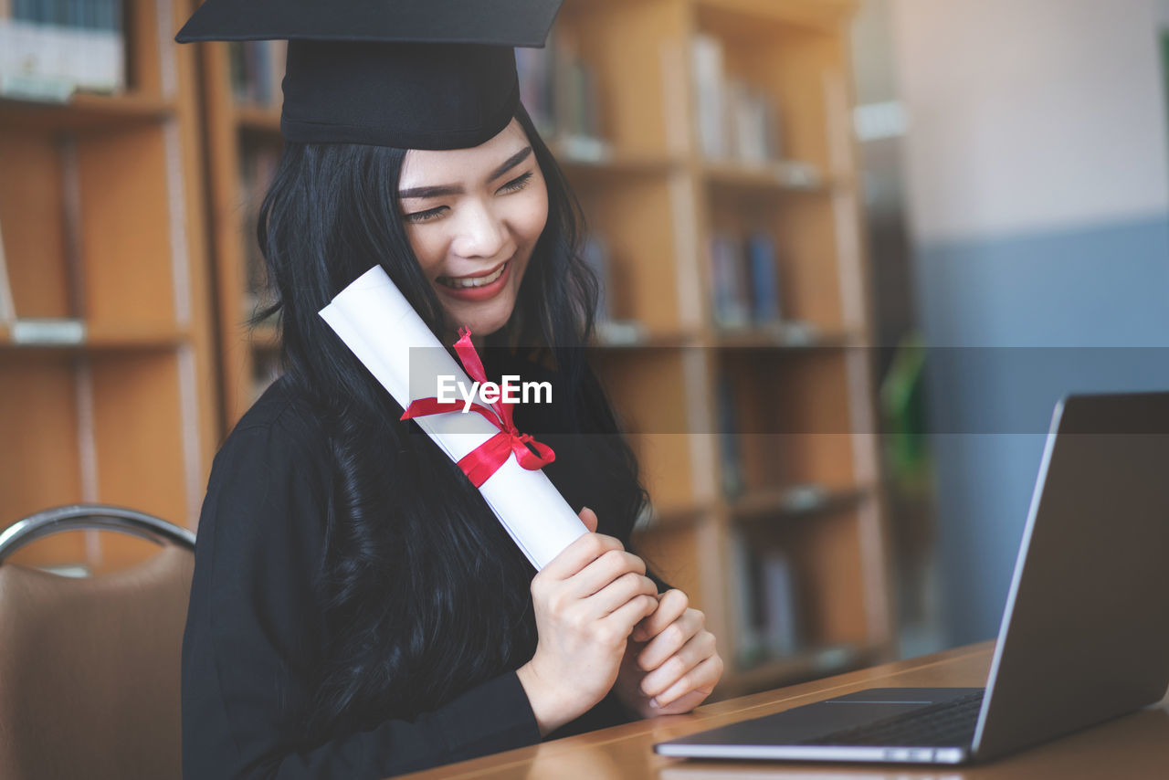 YOUNG WOMAN USING MOBILE PHONE IN THE LAPTOP