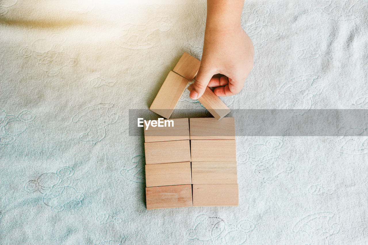 one person, indoors, wood, cardboard, hand, home ownership, high angle view, adult, childhood, paper, cardboard box, box, copy space, close-up