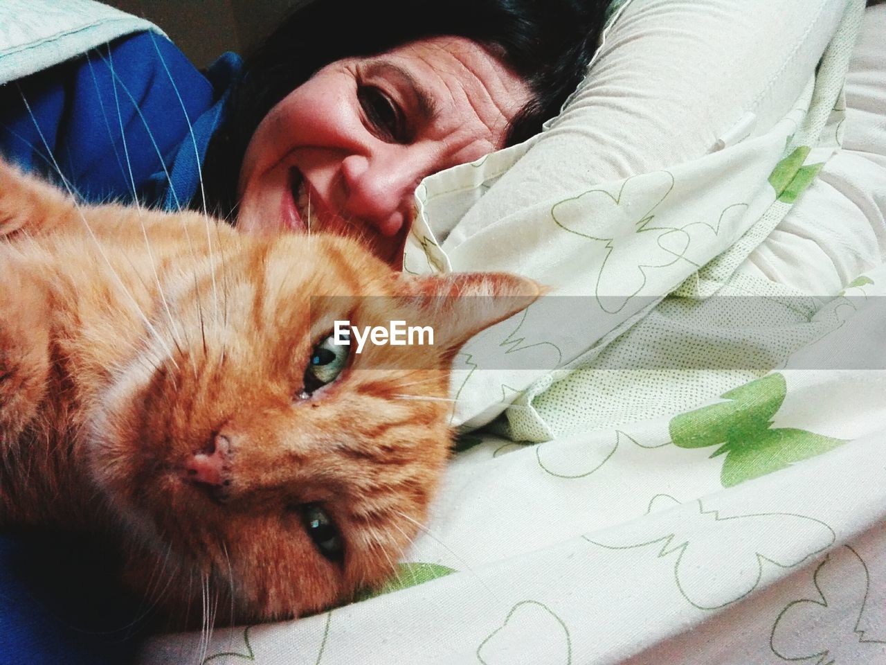 Close-up portrait of woman relaxing with cat on bed at home