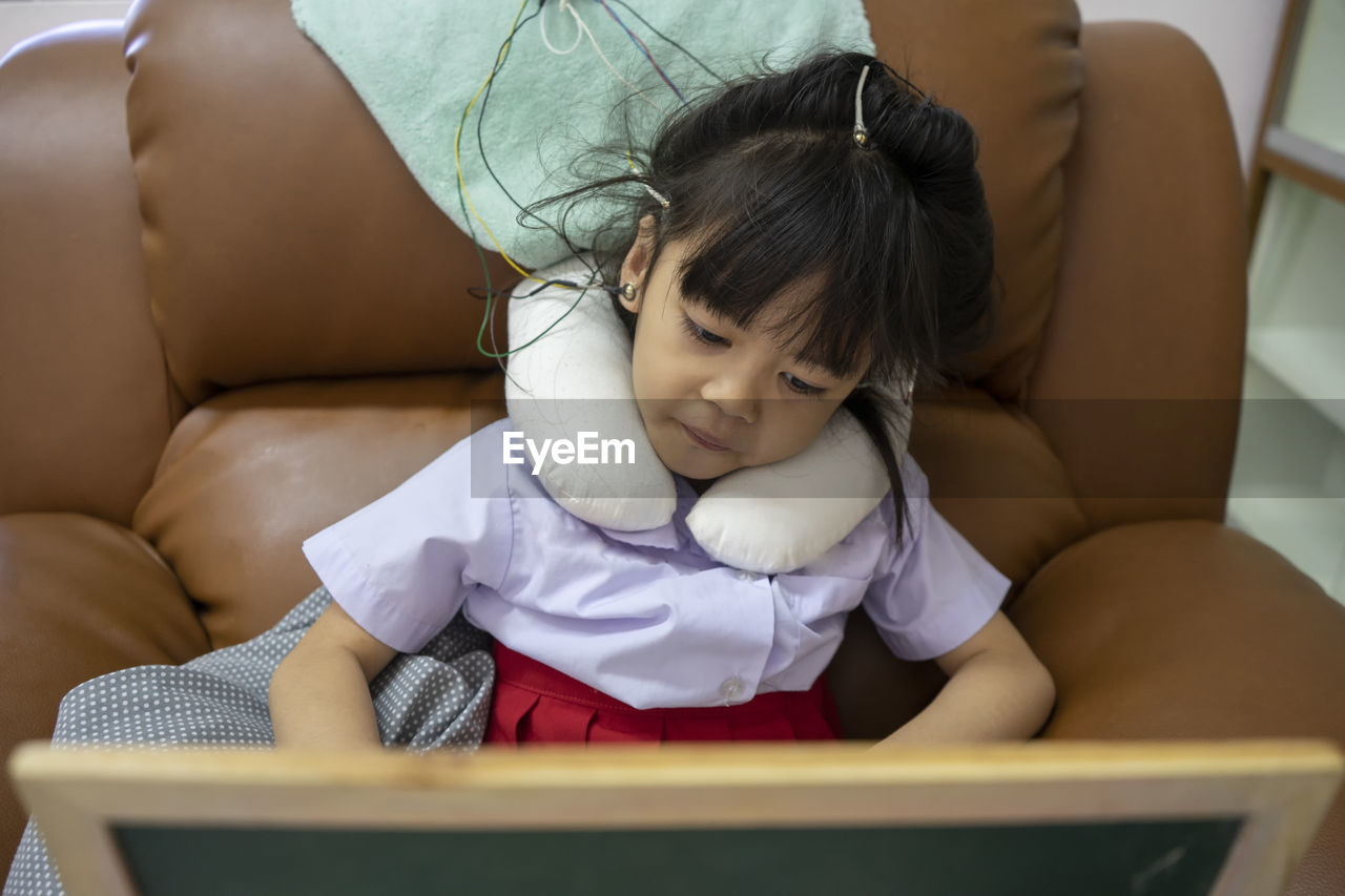 Cute girls with electrodes on head sitting on sofa