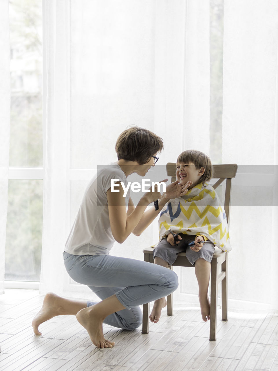 Mother giving hair cut to son at home