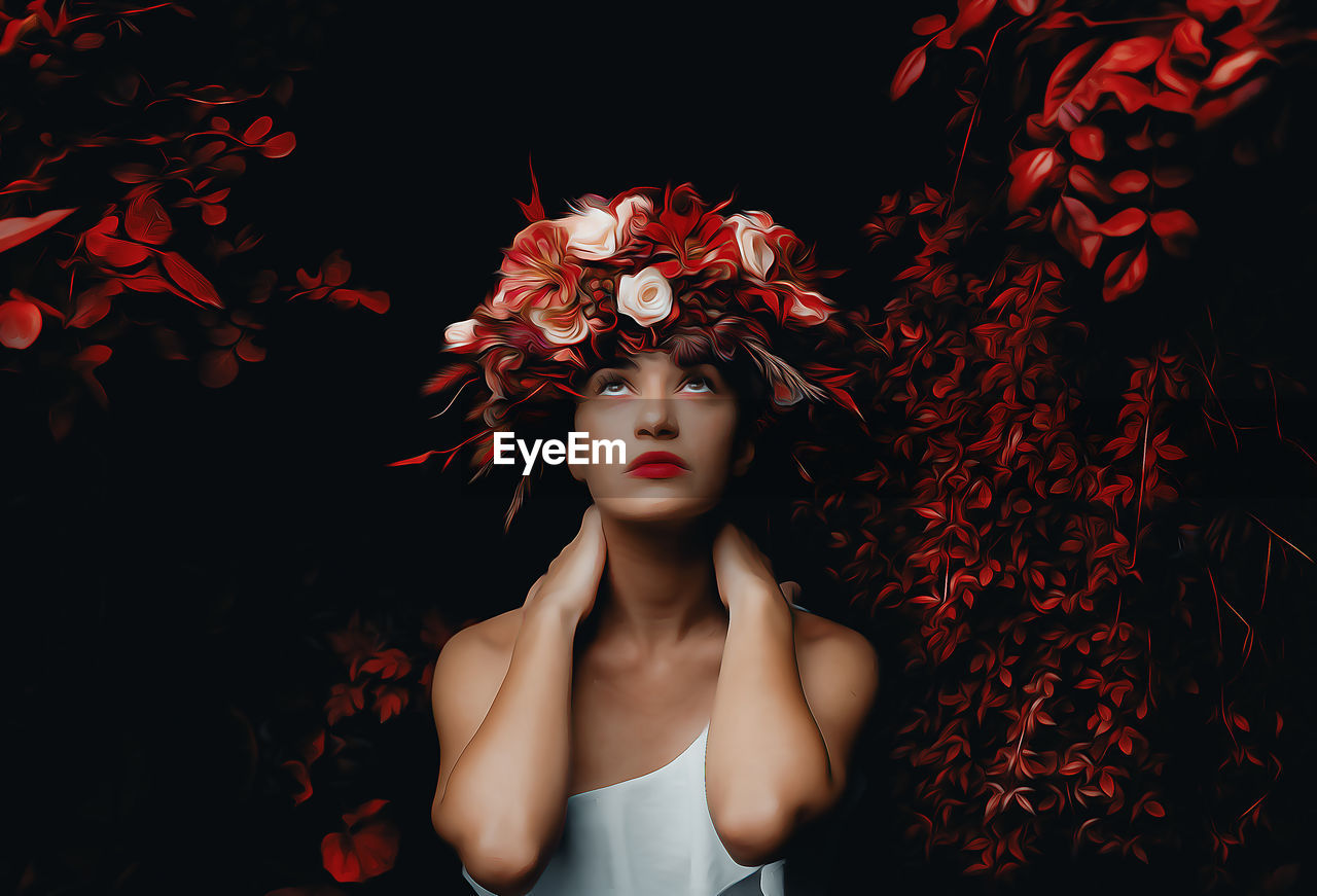 Portrait of young woman standing amidst plants at night