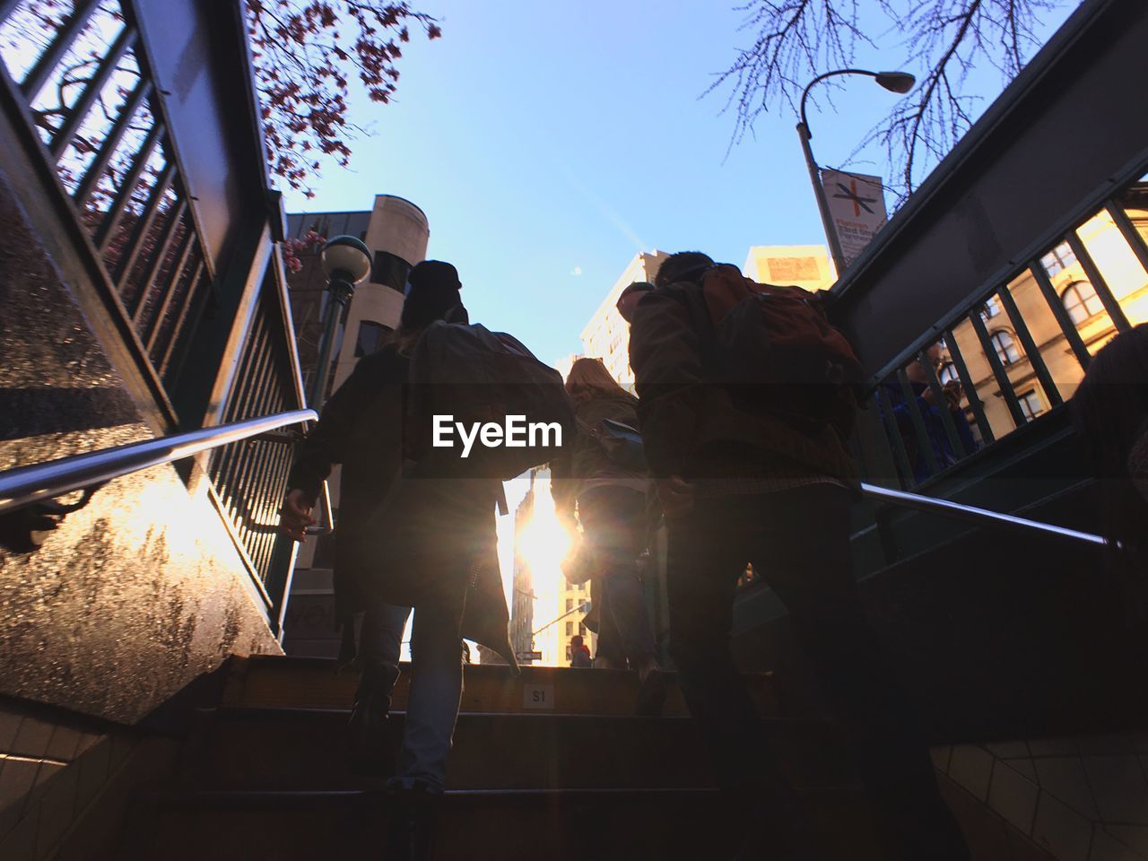 Low angle rear view of people walking on steps in city