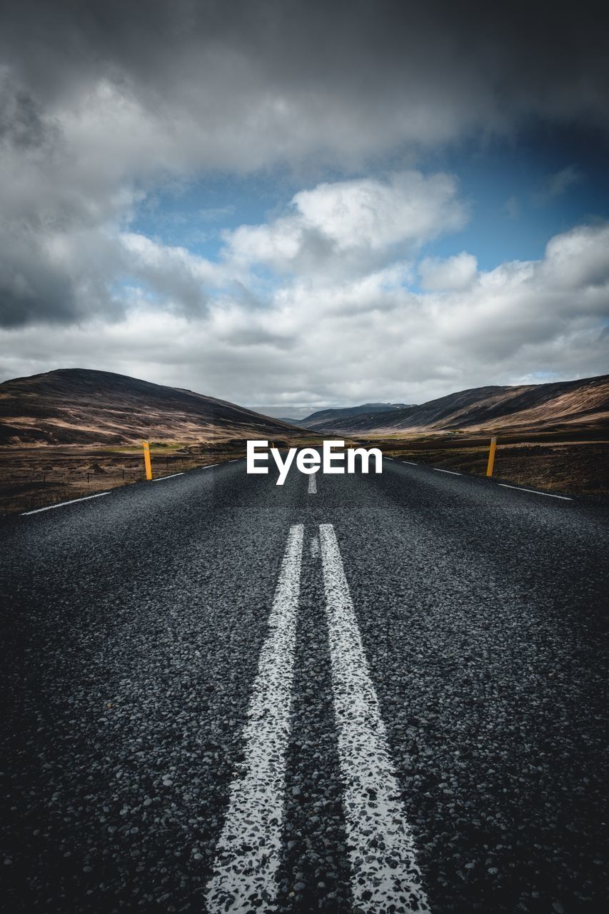 Surface level of country road against cloudy sky