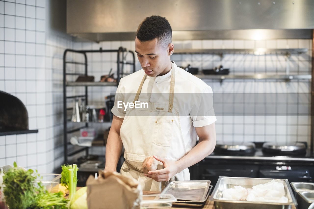 Confident male chef preparing food at kitchen counter in restaurant