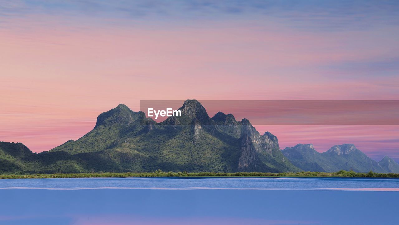 Scenic view of sea and mountains against sky during sunset