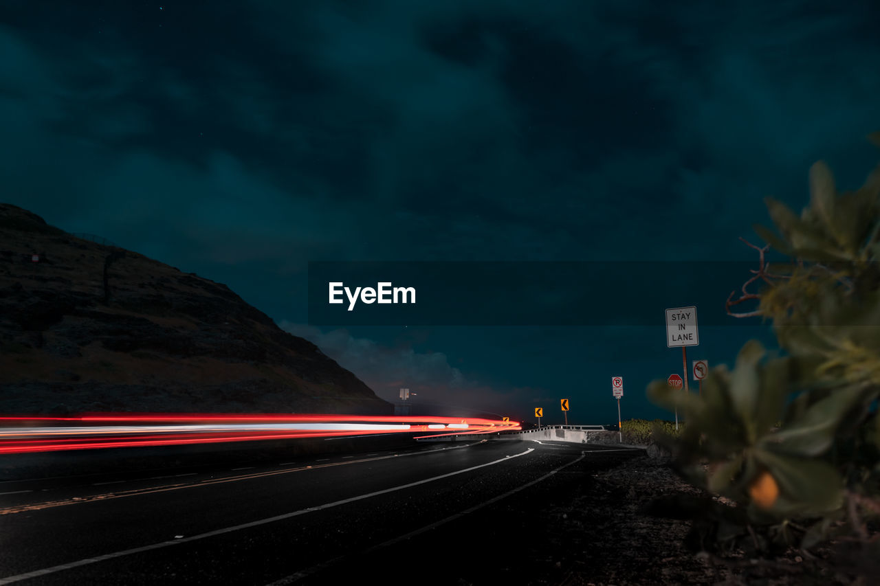 LIGHT TRAILS ON ROAD AGAINST SKY