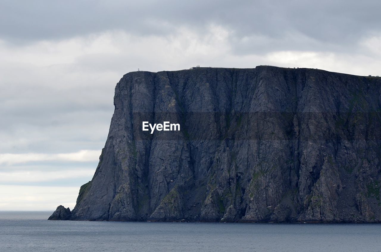 Rock formation by sea against sky