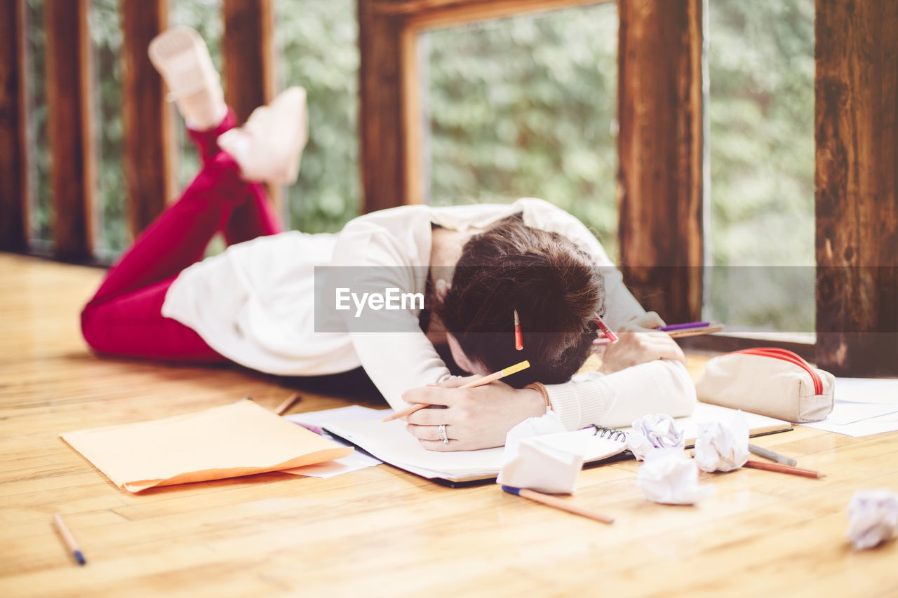 Tired woman lying over book on floor