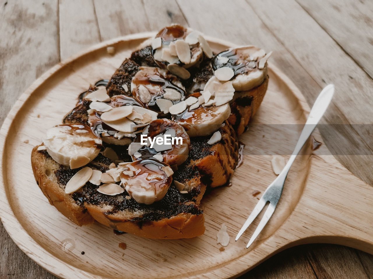 Close-up, chocolate toast with bananas and almonds. in dishe and wooden plate.