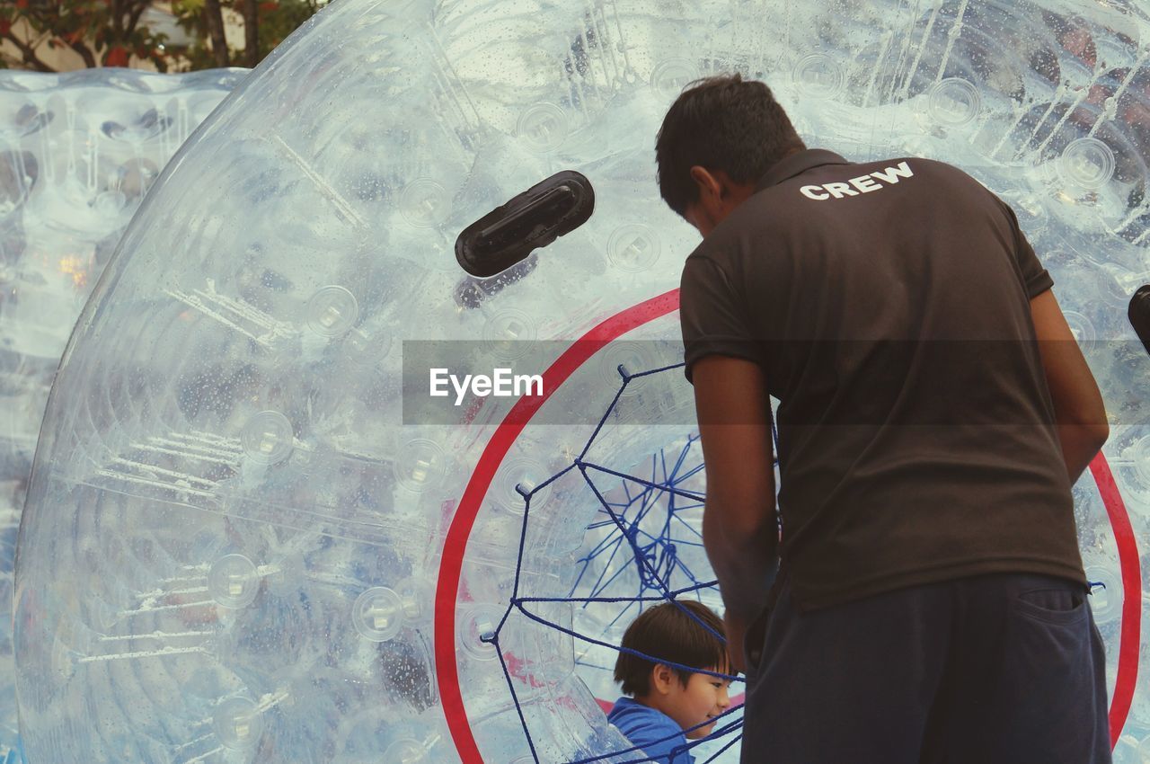 REAR VIEW OF BOY STANDING AGAINST GLASS