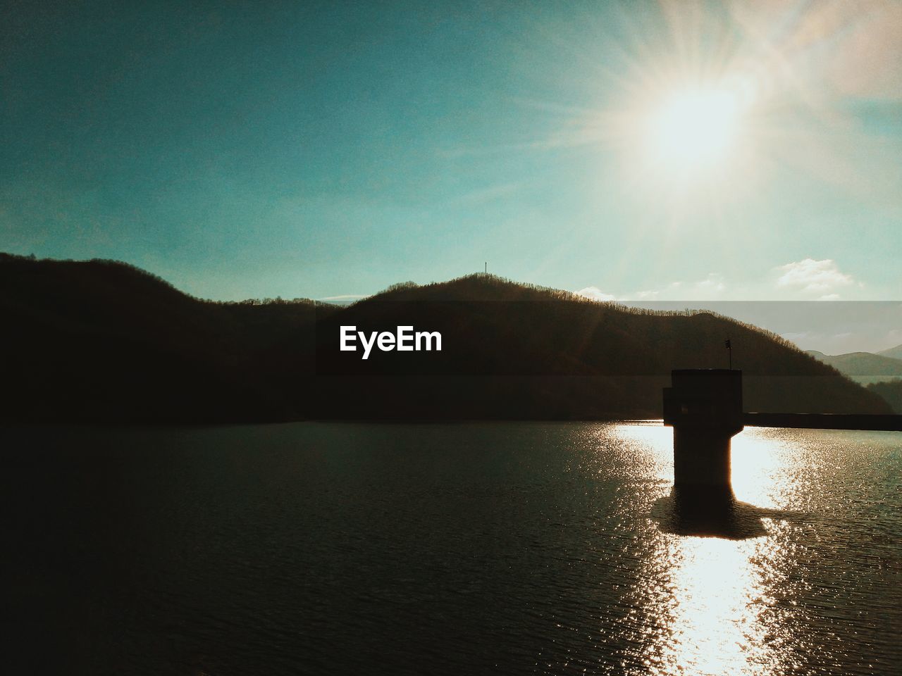 SCENIC VIEW OF LAKE AND SILHOUETTE MOUNTAINS AGAINST SKY