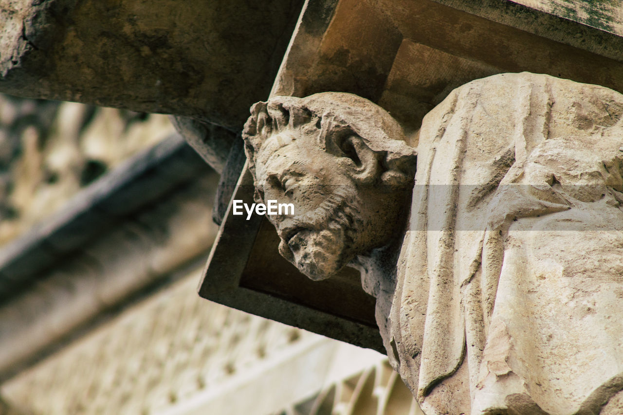 CLOSE-UP OF STATUE AGAINST OLD WALL