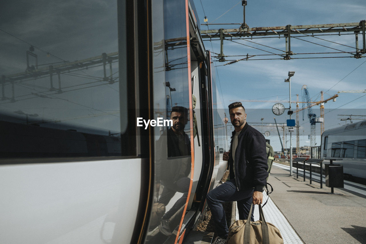 Side view of man with luggage entering in train at station