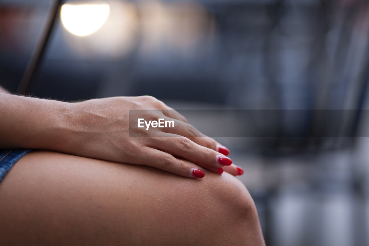 Midsection of woman with red painted fingernails