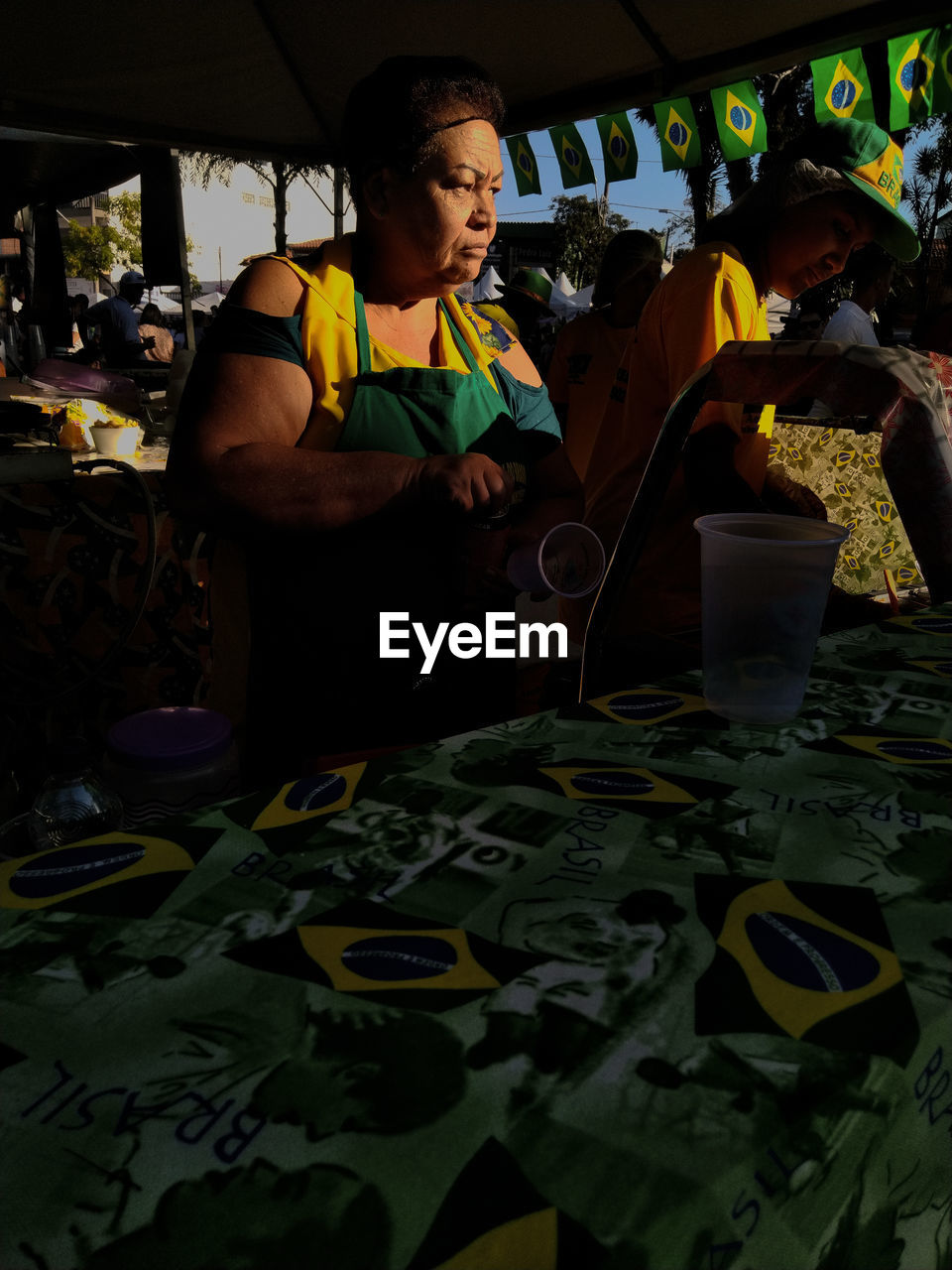 MAN WORKING ON TABLE WITH PEOPLE IN BACKGROUND