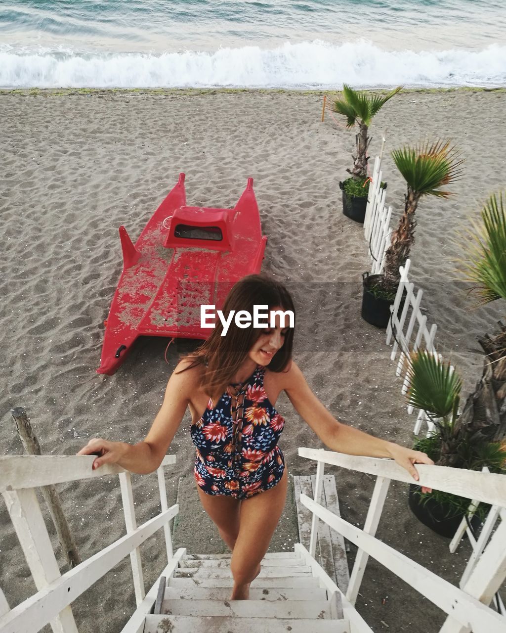 High angle view of young woman moving up on ladder at beach