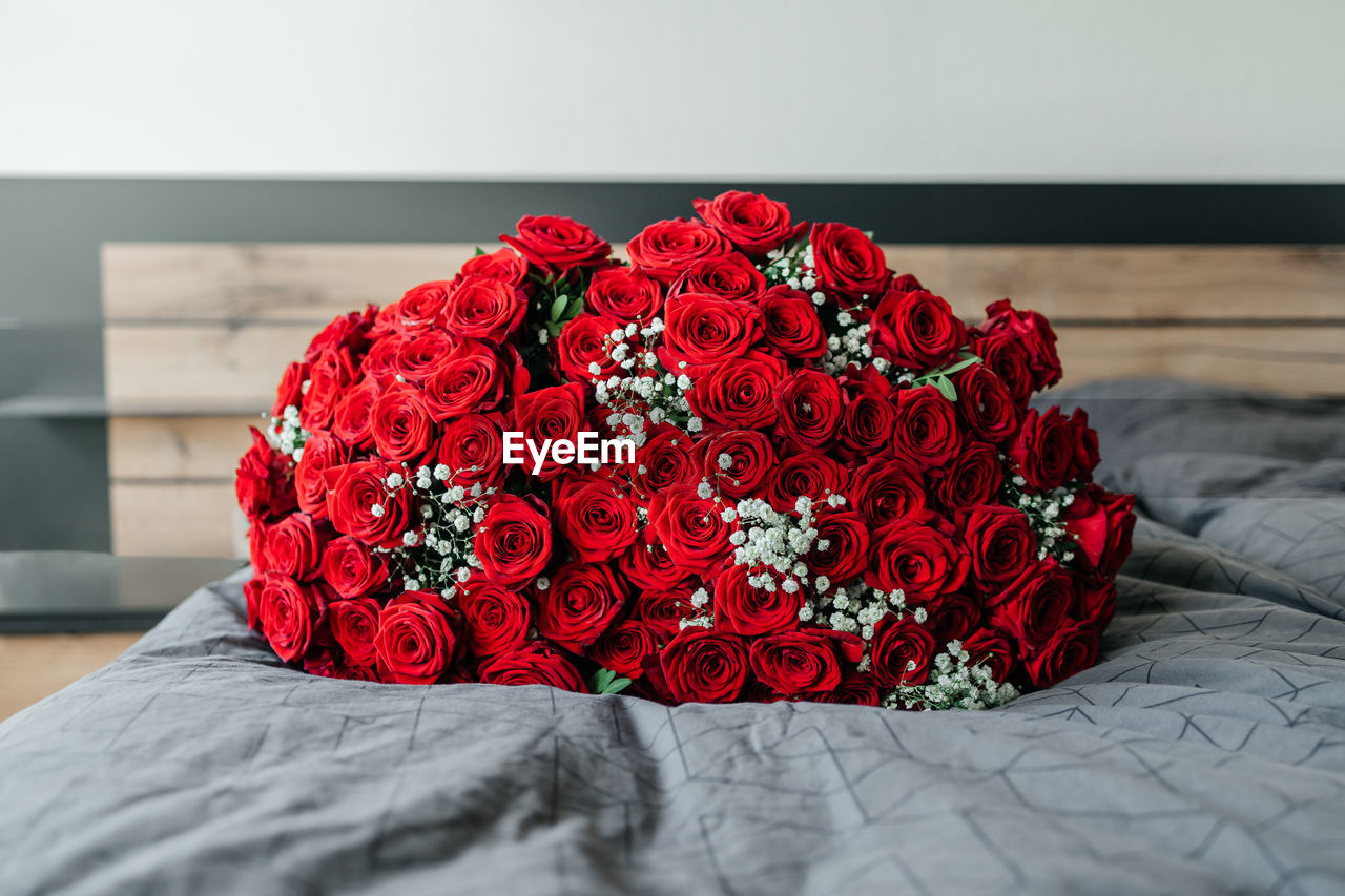 A huge beautiful bouquet of scarlet roses on a bed in a bedroom or hotel. flowers for the holidays