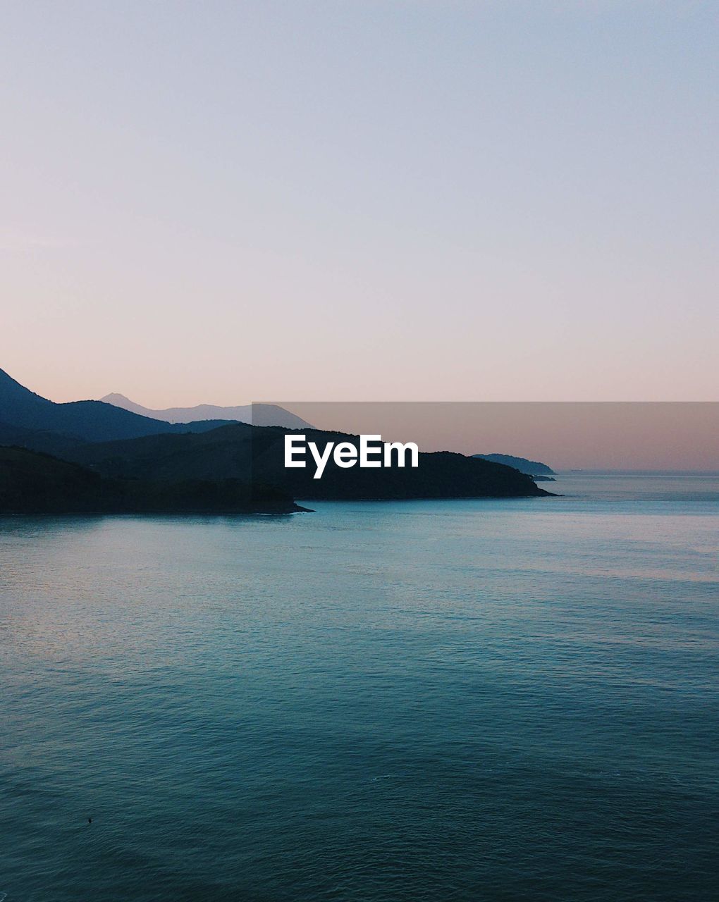 SCENIC VIEW OF SEA BY MOUNTAIN AGAINST CLEAR SKY