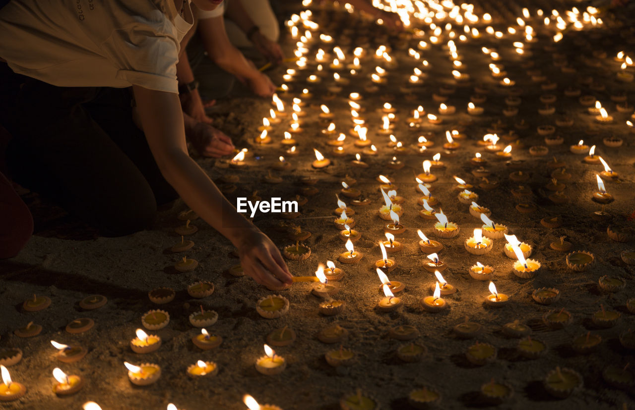 LOW ANGLE VIEW OF ILLUMINATED CANDLES ON TEMPLE