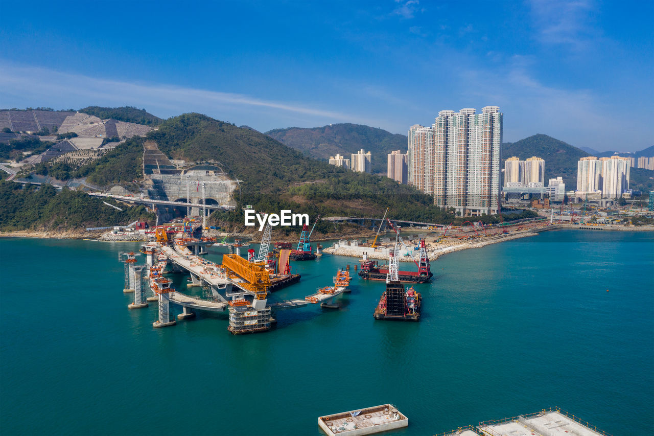 BOATS IN SEA BY BUILDINGS AGAINST SKY