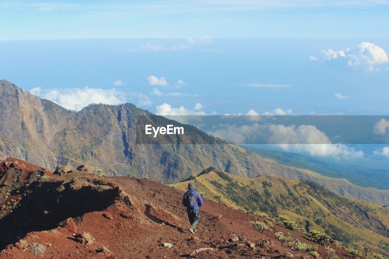 Rear view of man looking at mountains against sky