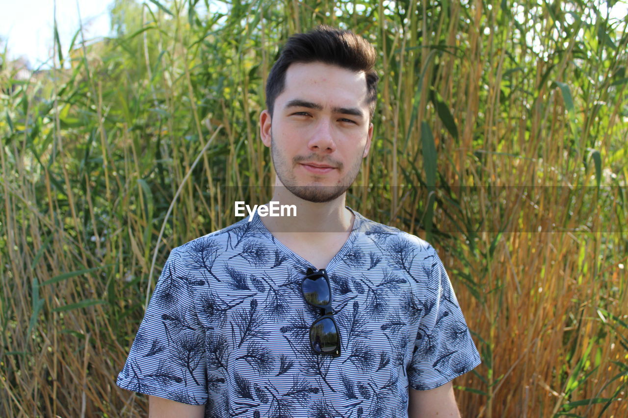 Portrait of young man standing against plants