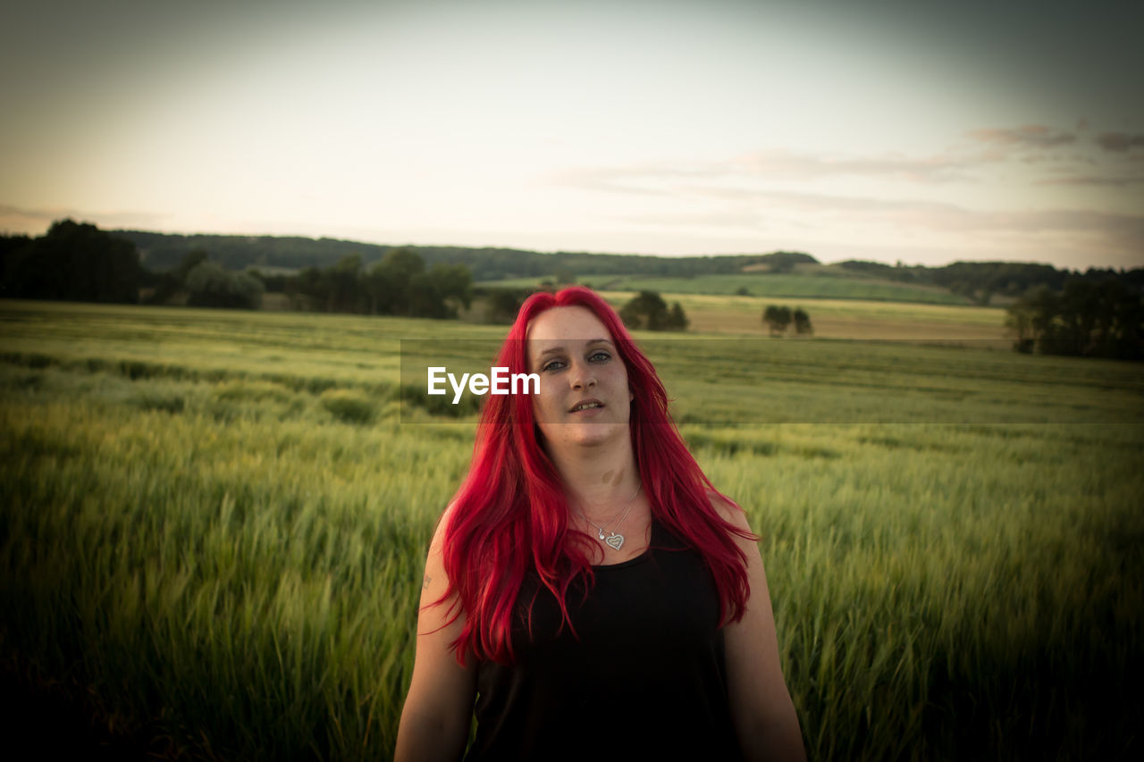 Portrait of redhead woman standing at farm