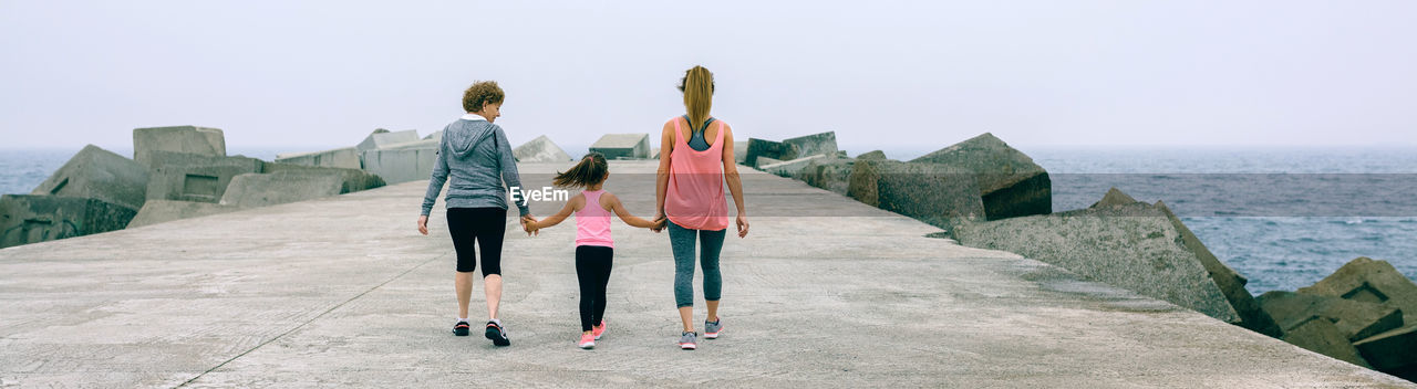 Rear view of family walking on pier