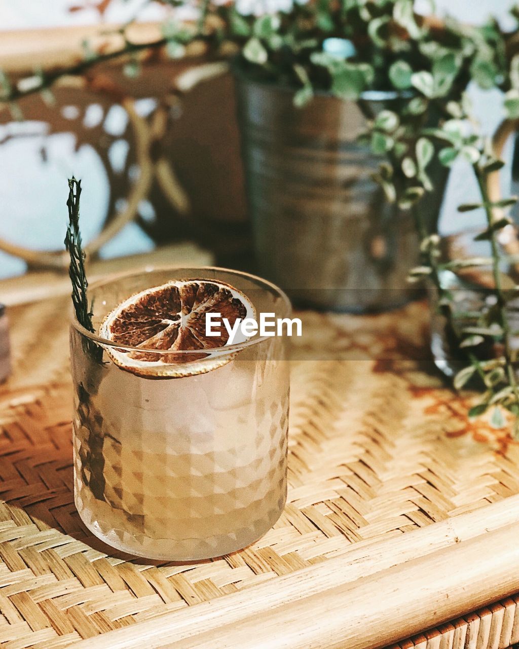 Close-up of yellow clear drink on boho shelf with potted plant