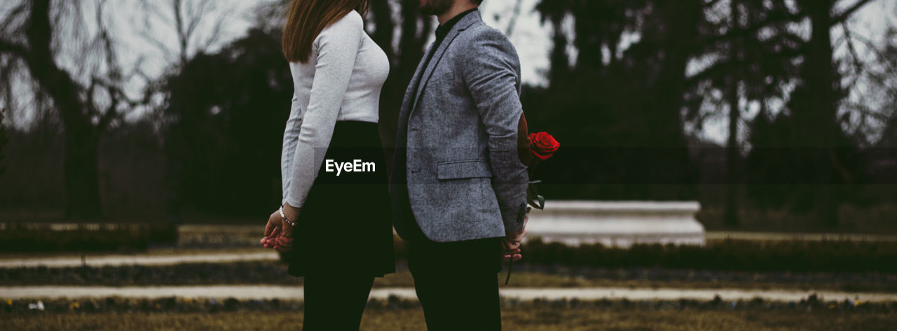 Midsection of couple standing on field